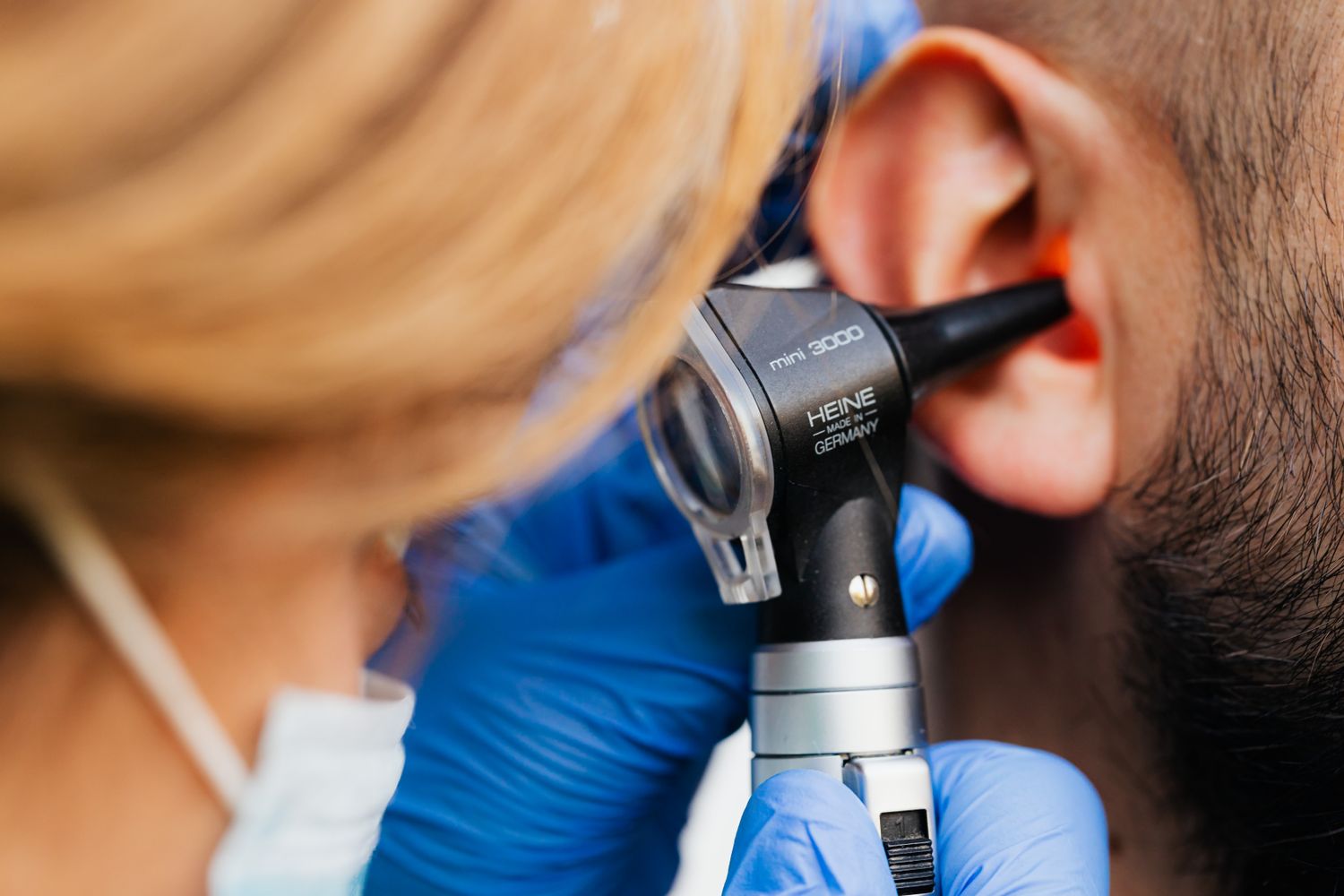 A clinician examining a patient's ear with an otoscope