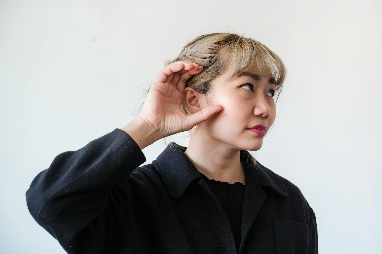 A woman cupping her hand behind her ear, straining to hear