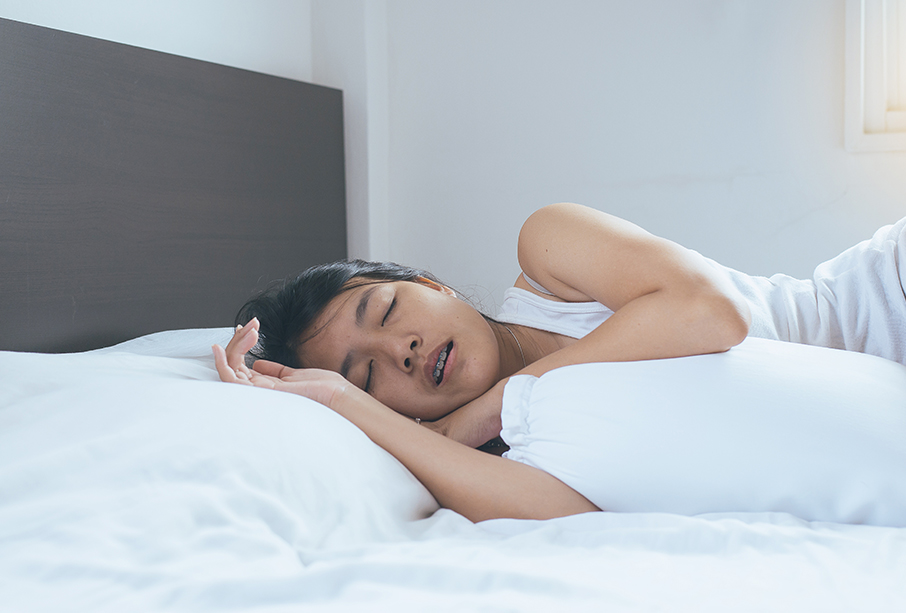 A woman asleep in bed with her mouth slightly open