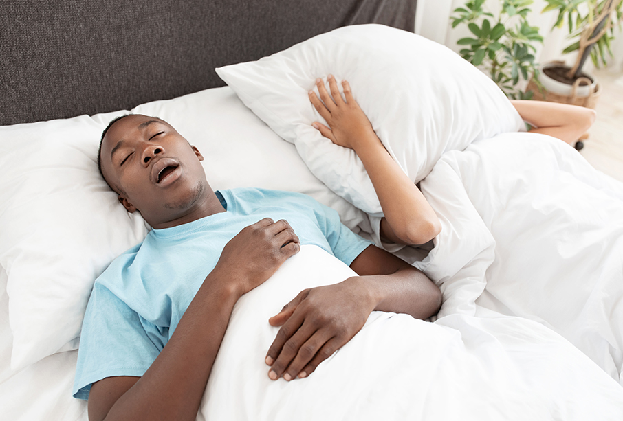 A man sleeping on his back with his mouth open, snoring loudly