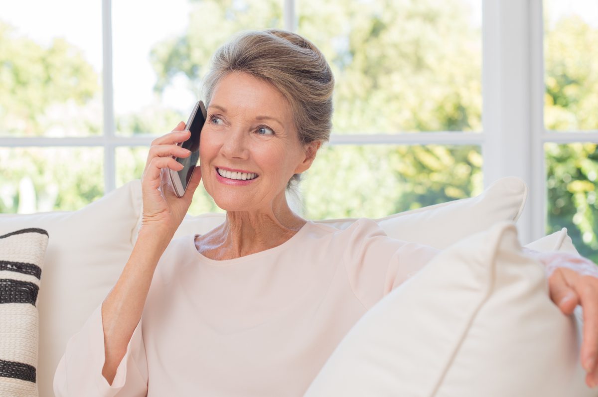 Woman smiling while talking on the phone on her sofa